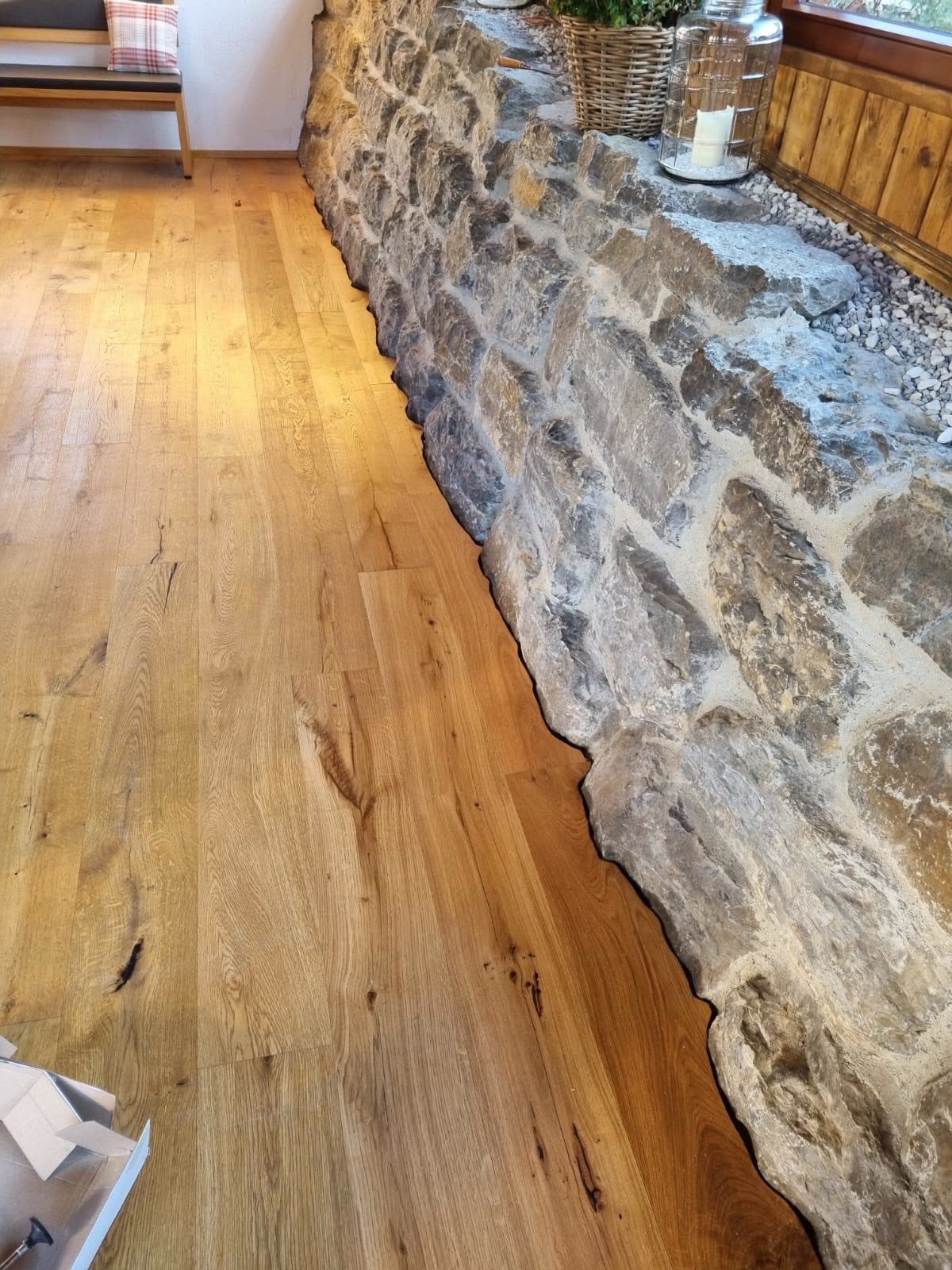 Fertig verlegter Holzboden an einer Natursteinwand